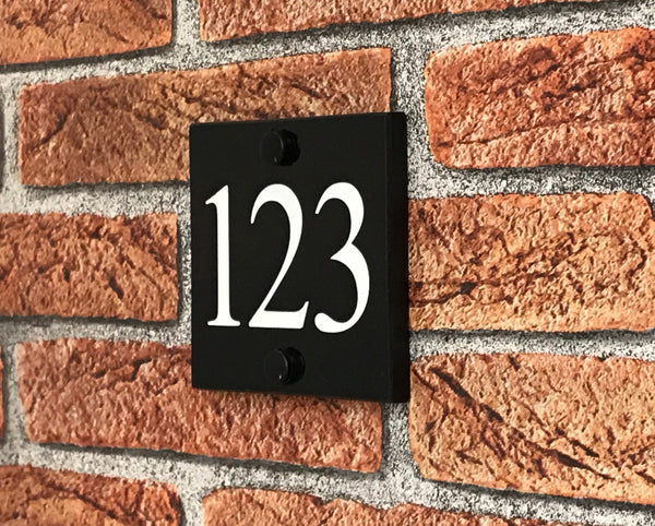 A black square House Sign with clear to see deep cut numbers featuring a green plant placed elegantly on its surface www.HouseSign.co.uk 